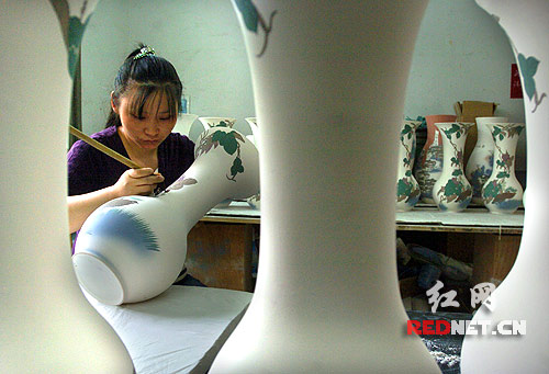醴陵醴泉窯藝的工人正在描繪釉下彩瓷瓶,陶瓷生產(chǎn)創(chuàng)造的價值約占醴陵國民生產(chǎn)總值的四成。